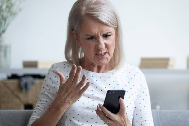 istock Unhappy middle aged lady irritated by bad smartphone work. 1251350048