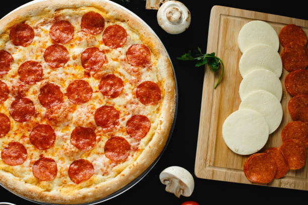 istock Pizza pepperoni with ingredients on a black background. Top view 1251351943