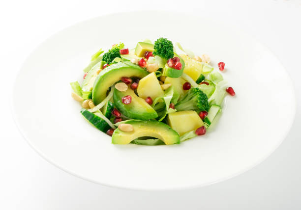 istock Green Salad with Avocado, Cucumber and Nuts on White Plate 1251352395
