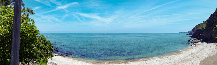 Panoramic landscape. There is an empty beach, and you can see the ocean and the horizon far away.