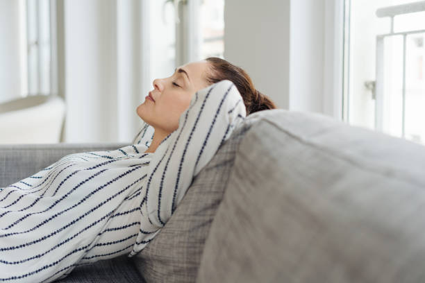 istock Tired young woman taking a nap resting on a sofa 1251353423