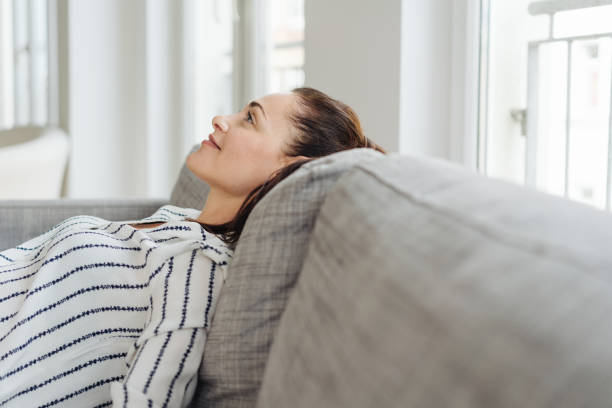 istock Young woman sitting daydreaming on a sofa 1251353975