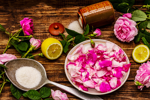 Ingredients for cooking rose petals jam. Sugar, lemon, fragrant flowers. Old wooden boards table