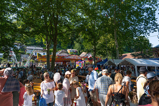 Children and adults talking and walking and visiting Lunapark and sitting under the trees in a sunny afternoon on the 4th of july at Jugendfest Brugg 2019.