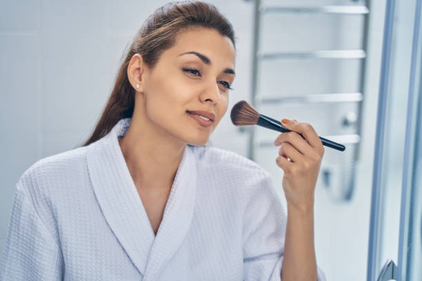 istock Charming young woman using makeup brush in bathroom 1251357634