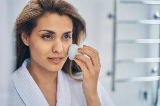 istock Attractive young woman using facial cleansing brush 1251357722