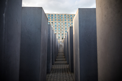 Berlin, Germany - May 07, 2019: View of the Memorial to the Murdered Jews of Europe, also known as the Holocaust Memorial (German: Holocaust-Mahnmal) Architect: Peter Eisenman. Clearly visible on the background is the building of the DZ Bank by architect Frank Gehry.