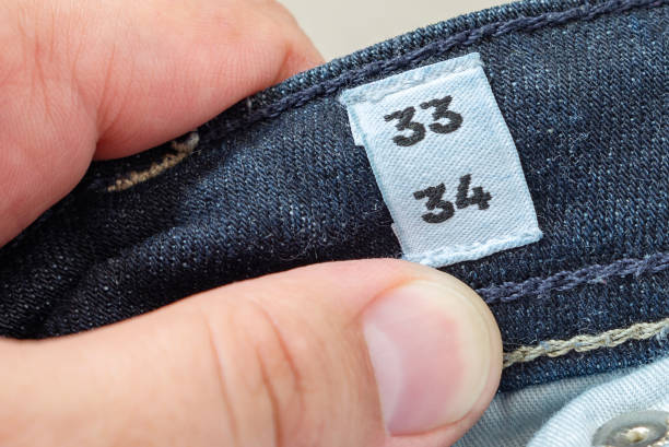 Men's hand holding jeans size label \