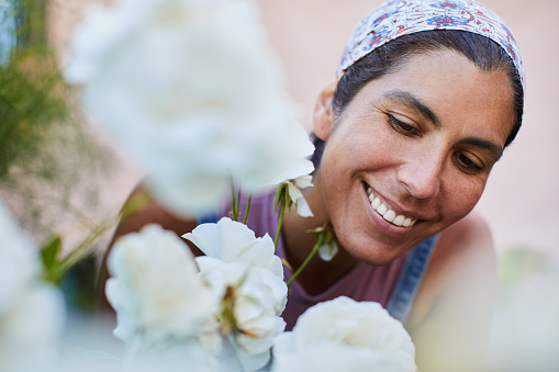 Closeup of a woman smiling while admiring the blooms of some white flowers growing in her garden