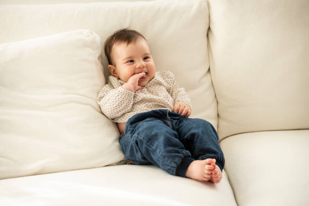ソファに横たわっているかわいい女の赤ちゃん - finger in mouth 写真 ストックフォトと画像