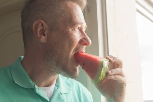 istock Man eats fresh, juicy slice of watermelon 1251369039
