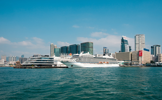 HongKong, Hong Kong - November, 2019: Cruise Ship docked at The Hong Kong cruise terminal - known as Ocean Terminal with Kowloon coast skyline background