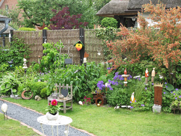 Beautiful garden in Gothenburg featuring a quaint seating area with decorative white chairs and a small table, complemented by lush plants and a striking red wooden house.