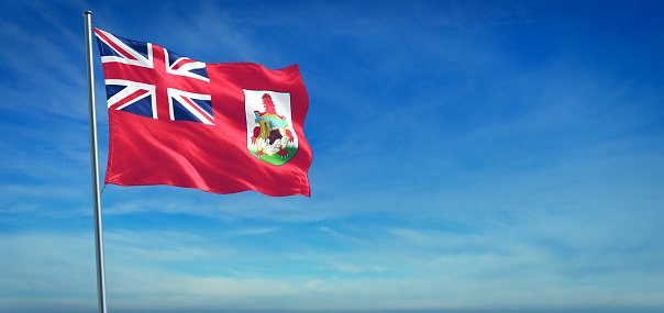 The National flag of Bermuda blowing in the wind in front of a clear blue sky