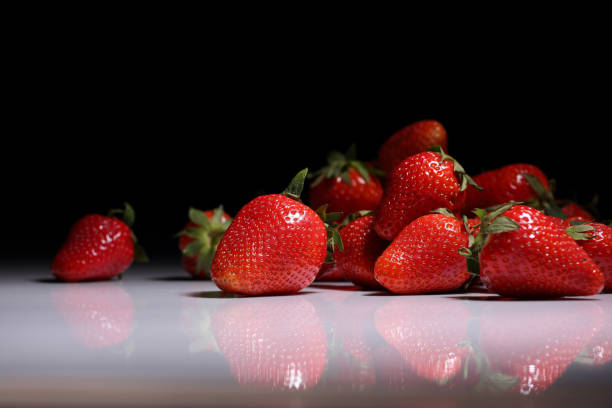 Strawberry berries on a glossy table and dark background Ripe, juicy strawberries on a white glossy table and dark background dissert stock pictures, royalty-free photos & images