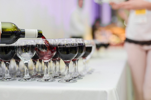 Filling wine glasses on a buffet table in restaurant.