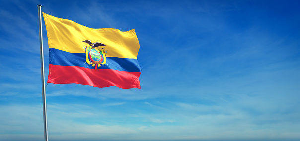 The National flag of Ecuador blowing in the wind in front of a clear blue sky