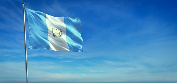 The National flag of Guatemala blowing in the wind in front of a clear blue sky