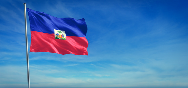 The National flag of Haiti blowing in the wind in front of a clear blue sky