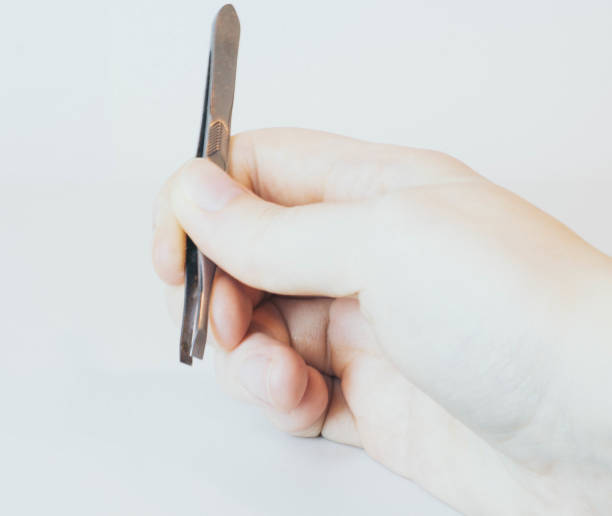 istock Hand with old tweezers on a white background 1251376225