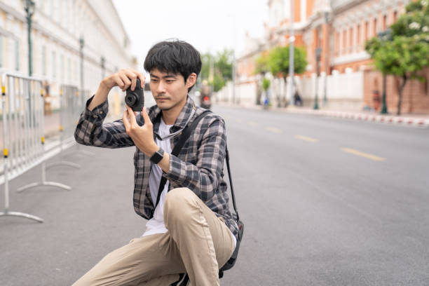 istock Young man tourist holding a camera and taking photos. 1251377395