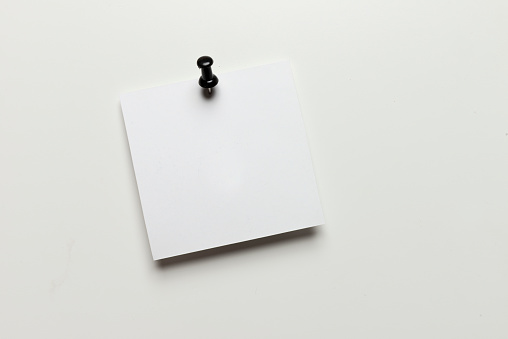 Blank white paper attached with thumbtack on white background.