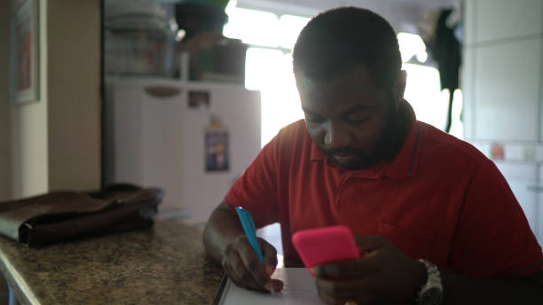 istock Portrait of a man working - doing reminder note on note pad and using mobile phone 1251378707