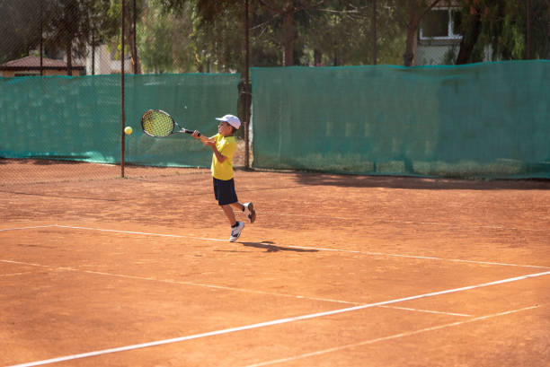 un niño está disparando de derecha en la cancha de arcilla - forehand fotografías e imágenes de stock