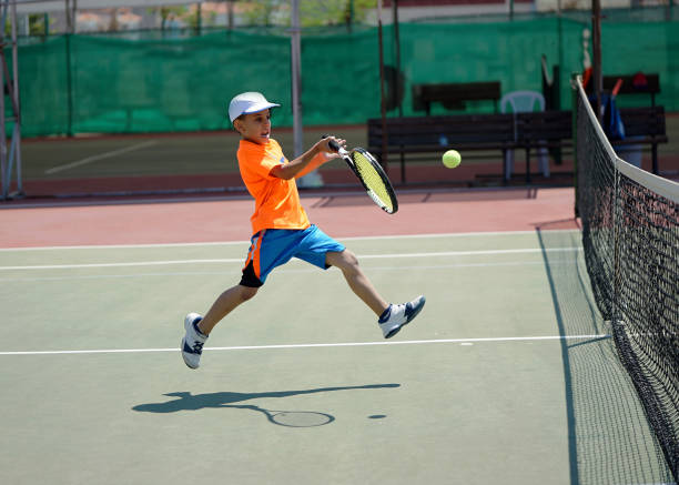 a boy is playing tennis on the hardcourt with forehand - tennis equipment imagens e fotografias de stock