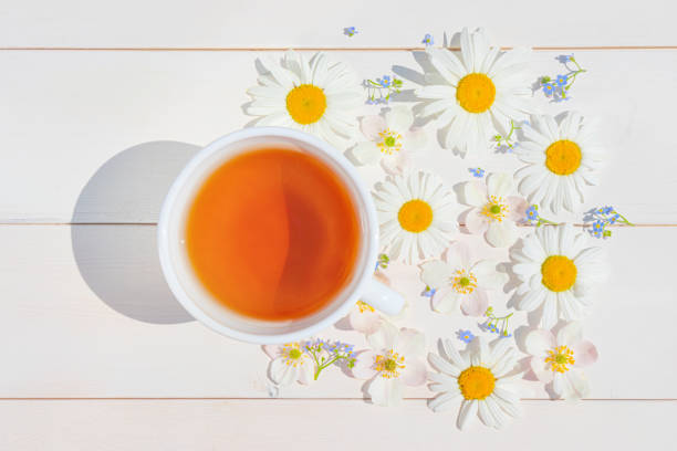 istock Chamomile tea in a white little cup on a light wooden surface. 1251380929
