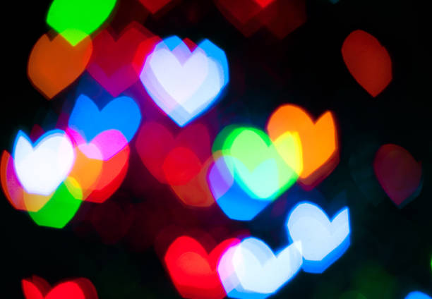 istock Glowing and festive colored light hearts created from in camera and lens bokeh. Christmas fairy lights defocused giving a blurred effect. Background for design.