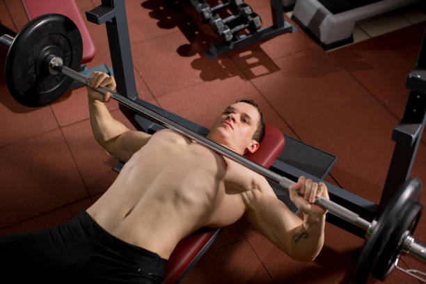 istock Brutal athletic man pumping up muscles on bench press 1251383109