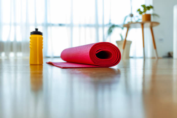 Red exercise mat on the floor Gym equipment for fitness exercise, dumbbells and Yoga mat in room. bottled water on table stock pictures, royalty-free photos & images