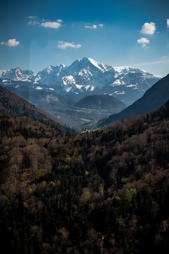 A mountain range in Salzburg, Austria with snowy peaks and a valley of trees in the foreground. Travel, tourism, getaway concepts
