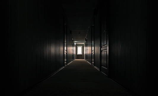 gloomy dark corridor with closed doors of an empty hotel without people during quarantine