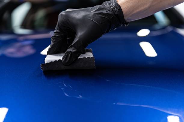 istock Man worker of car detailing studio applying ceramic coating on car paint with sponge applicator. 1251386156
