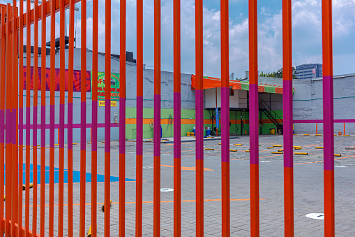 Bogota, Colombia - March 28, 2020: This public car park and car wash in the capital city is empty due to the Covid-19 lockdown declared by the local government in the Capital city. Not a single car is in the area. The brightly painted gate is shut. Image shot on a bright, sunny morning with clear skies. Horizontal format. Copy space.