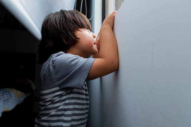 istock Boy looks out the window while greeting and playing alone in Quarantine times 1251396878