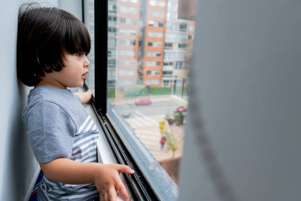 istock Boy looks out the window while greeting and playing alone in Quarantine times 1251396916