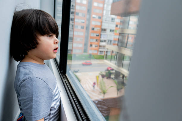 istock Boy looks out the window while greeting and playing alone in Quarantine times 1251397020