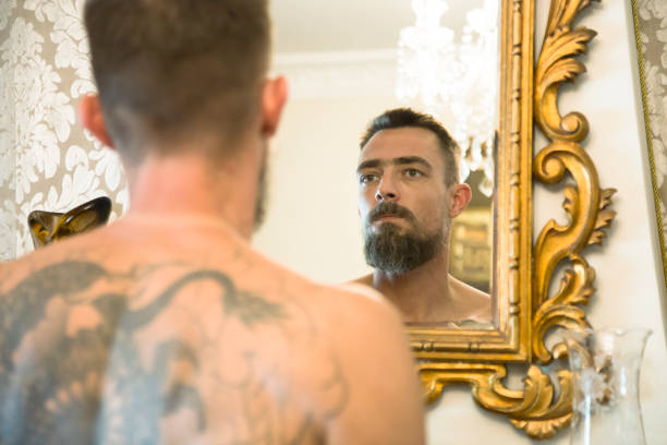 istock Tattooed man looking at himself in the mirror 1251397046