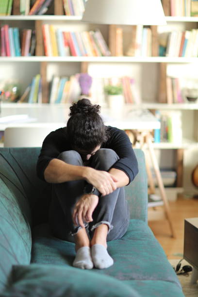 istock Man sitting alone at home looking sad and distraught 1251398487