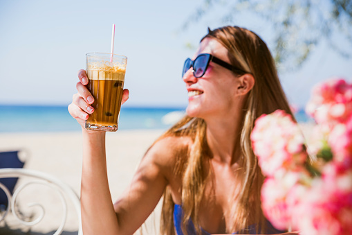 Young smiling woman with frappe coffee on summer vacation