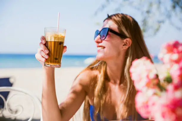 Young smiling woman with frappe coffee on summer vacation