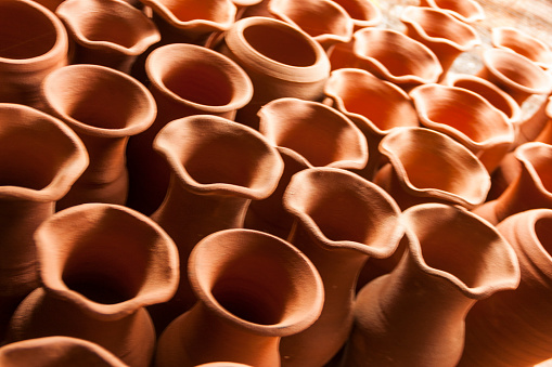 A pile group of chilean classic rustic handmade baked earthenware empty terra-cotta greda clay flower pots for sale at the pottery workshop in Pomaire, Chile
