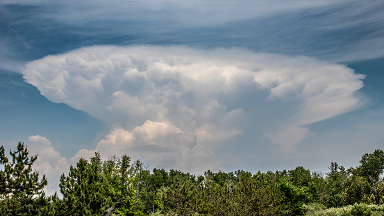 A thunderstorm cloud from a distance over a rural setting.
