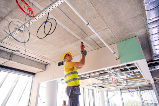istock Young male construction worker in yellow hardhat drilling the wall with electric drill tool. Close-up front portrait with copy space 1251409036