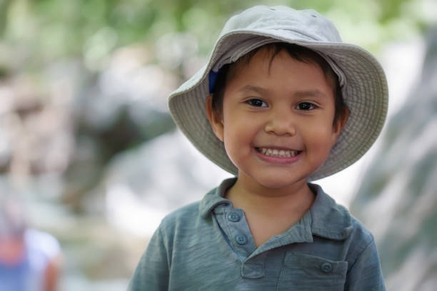 Young hispanic boy wearing a fishing hat that is smiling and looks happy in a natural outdoor setting. stock photo