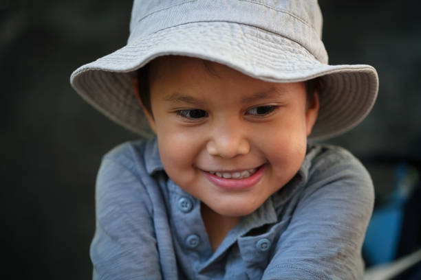 A little boy wearing a fisherman's hat and smiling, expressing happiness while fishing. stock photo