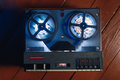 blue led light strip reels on reel to reel tape recorder, close-up view